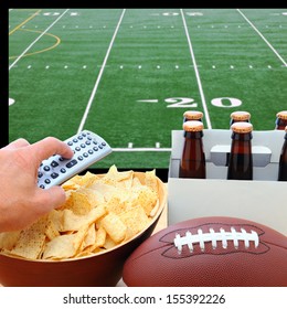 Closeup of a man's hand holding a TV remote with a bowl of chips and a six pack of beer with a football field on the television screen in the background. Square Format.