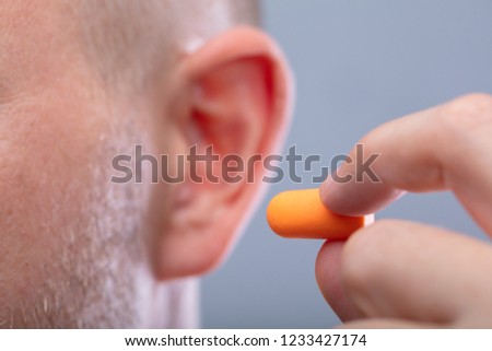 Close-up Of A Man's Hand Inserting Earplug In His Ear