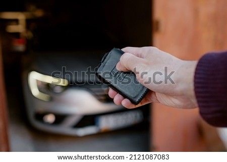Close-up of a man's hand locking or unlocking a car with keyless in garage. Black leather case for keyless