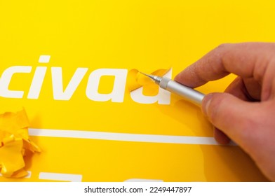 Close-up of a man's hand making a car sticker from yellow foil