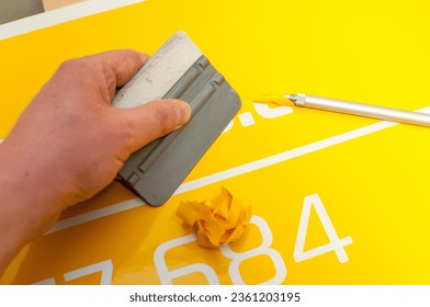 Close-up of a man's hand making a car sticker from yellow foil