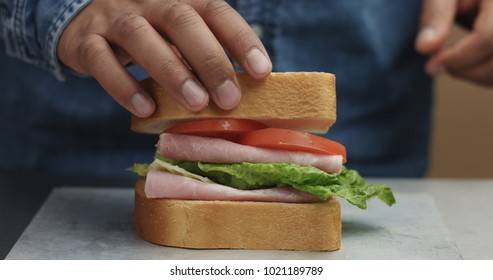 Closeup Of Man's Hand Making Sandwich, Puts From Sides All Ingredients On Plate