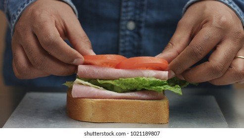 Closeup Of Man's Hand Making Sandwich, Puts From Sides All Ingredients On Plate