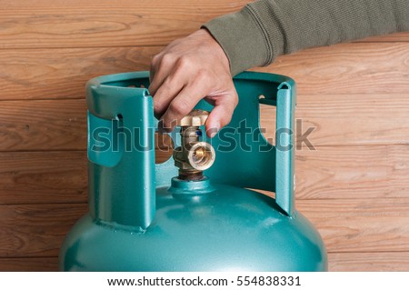 Closeup man's hand operating valve of LPG cylinder for cooking