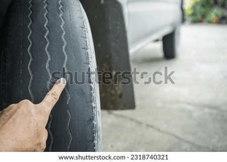 Close-up of man's hand pointing at old worn and bald tires from use. concept of tire wear and the dangers of using old tires.