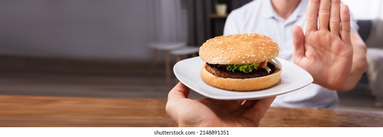 Close-up Of A Man's Hand Refusing Burger Offered By Person