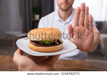 Close-up Of A Man's Hand Refusing Burger Offered By Person