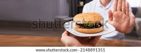 Close-up Of A Man's Hand Refusing Burger Offered By Person