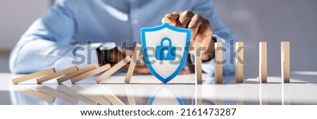 Close-up Of A Man's Hand With Shield Security Icon Stopping Dominoes From Falling