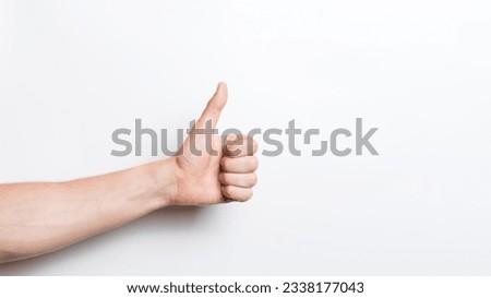 Close-up of a man's hand showing a thumbs up gesture isolated on a white studio background.