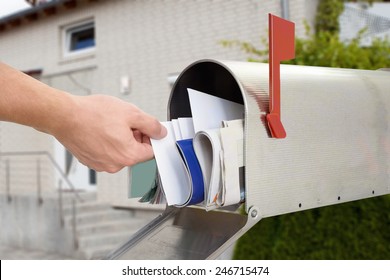 Close-up Of Man's Hand Taking Letter From Mailbox Outside House