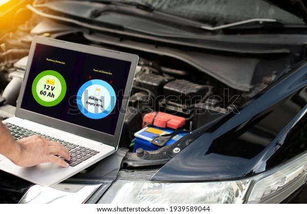 Closeup, man\'s hand typing on laptop computer\
keyboard to check the operation of the car engine in the garage.\
The engine of a car does not start. Notebook computer screen shows\
battery and oil status