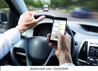 Close-up Of A Man's Hand Typing Text Message On Mobile Phone While Driving Car - Shutterstock ID 1164153049