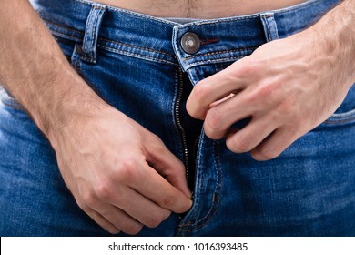 Close-up Of A Man's Hand Unzipping The Blue Jeans