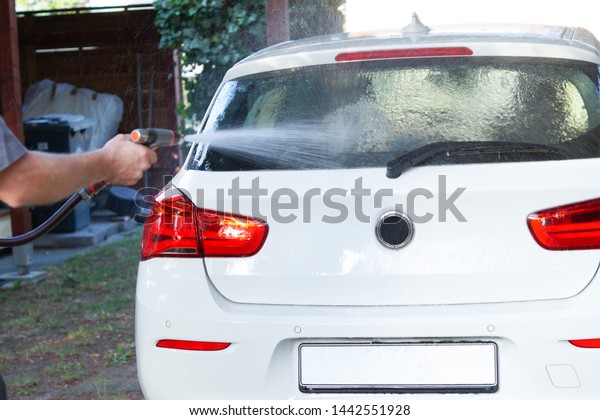 Closeup man\'s hand is washing a car. Hand holds\
sponge to wash car. Cleaning automobile with sponge. Car washing\
and cleaning concept.