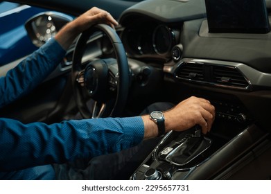 Close-up of a man's hand while shifting the automatic transmission of a car.