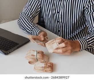 A close-up of a man's hands counts a bundle of bills for five thousand Russian rubles. Man counts red paper 5000 rubles bills. Russian cash money in male hand. A man holds a wad of money in his hands.