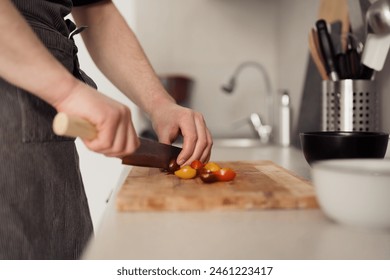 Close-up of a man's hands cutting tomatoes on a chopping board in a kitchen. - Powered by Shutterstock