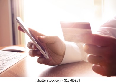 Closeup of man's hands holding credit cards and using mobile phone. Concept for m-commerce, online shopping, m-banking, internet security.