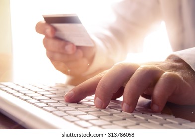 Closeup of man's hands holding credit card and using computer keyboard. Concept for e-commerce, online shopping, e-banking, internet security.