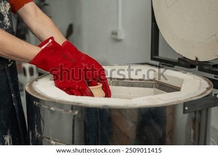 Close-up of a man's hands loading ceramics into a special kiln. 