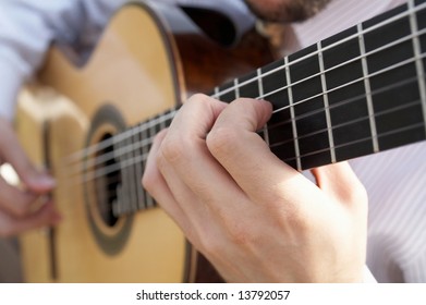 Closeup of man's hands playing classical acoustic guitar DOF focus on hand