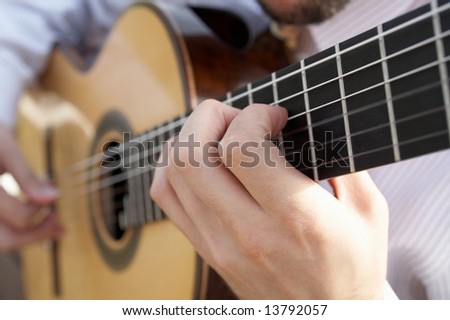 Closeup of man's hands playing classical acoustic guitar DOF focus on hand