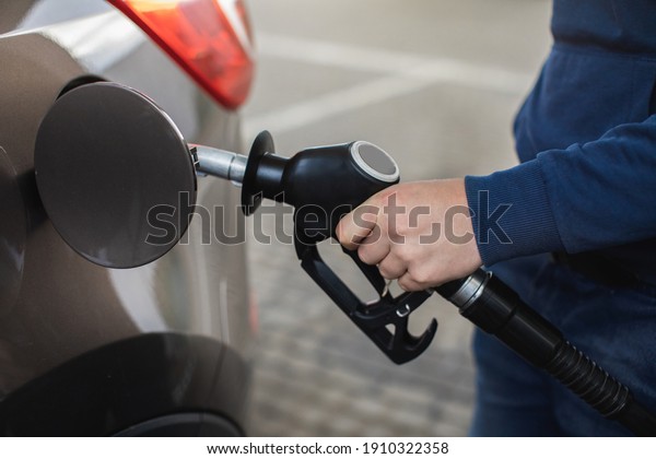 Closeup of man\'s hands pumping gasoline fuel in car\
at gas station. Petrol or gasoline being pumped into a motor\
vehicle car.