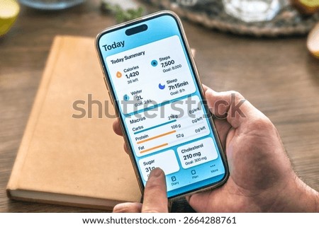 Close-up of a man's hands using a smartphone health app on a wooden table. Healthy lifestyle concept