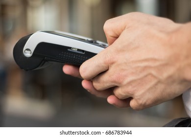 Close-up: Man`s Hands Are Working With A Debit Card Reader. It's A Popular Way To Pay A Bill By Hand Swiping Credit Card In Store, Restaurant Or Café Today. Get Paid Faster. Concept: Demonetization. 