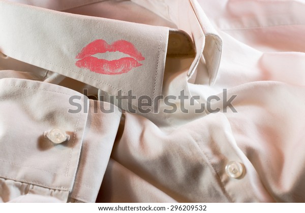 Close-up of a man\'s white\
business shirt with a smudge of a woman\'s bright red lipstick on\
the collar