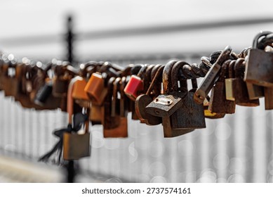 Closeup of many rusty padlocks attached to a metal railing, symbolising love and commitment.