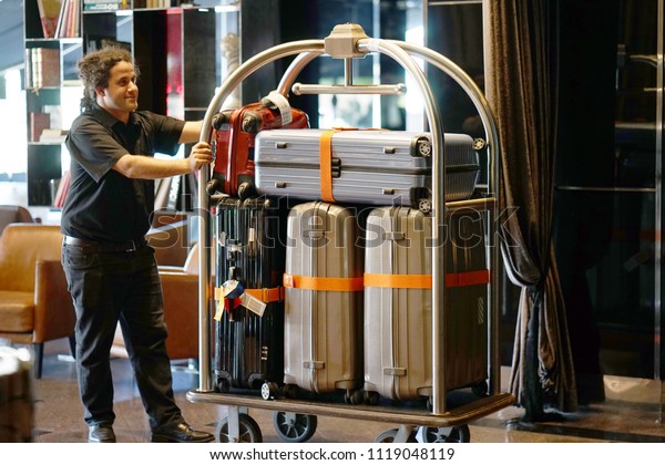 Closeup\
many suitcases on hotel luggage cart moving by bell boy. Baggage\
porter or bell boy bringing the suitcase of guests with a box van\
to the hotel room. Trolley Luggage at the\
hotel.