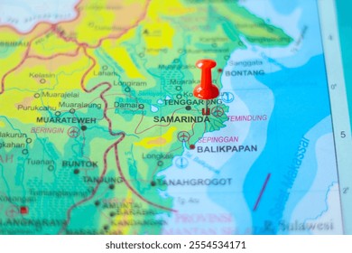 Close-up of a map with a red pin marking Samarinda, Kalimantan Timur, Indonesia. Shows geographical details and travel planning.