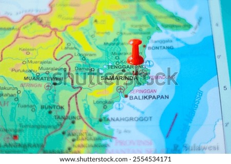 Close-up of a map with a red pin marking Samarinda, Kalimantan Timur, Indonesia. Shows geographical details and travel planning.
