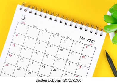 Close-up March 2022 desk calendar on yellow background.