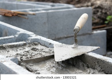 Closeup of mason's trowel on concrete shuttering blocks filled with mortar