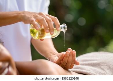 Closeup of masseuse hands pouring aroma oil on woman back. Woman prepare to do oriental spa massage for relaxing treatment. Therapist doing aromatherapy oil massage on girl body. Body care concept.