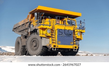 Closeup Massive yellow mining dump truck on snow covered coal field, banner.