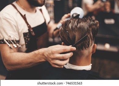 Close-up, master Barber does the hairstyle and styling with dryer, dries hair to guy. Concept Barbershop. Soft focus.