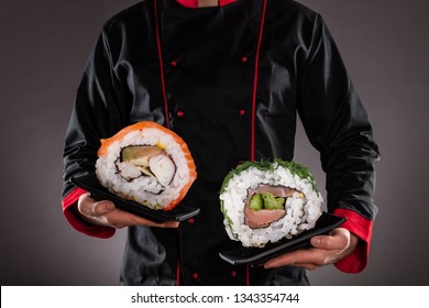 Closeup of master chef holding plates with giant sushi pieces. Concept of asian food