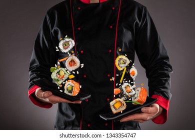 Closeup of master chef holding plates with flying sushi pieces. Concept of asian food