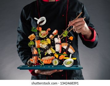 Closeup of master chef holding wooden chopsticks with flying sushi pieces. Concept of food preparation, ready for product placement.