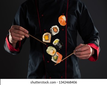 Closeup of master chef holding wooden chopsticks with flying sushi pieces. Concept of food preparation, ready for product placement.