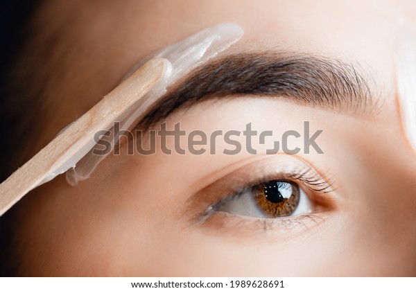 Closeup Master wax depilation of eyebrow hair\
in women, brow\
correction.