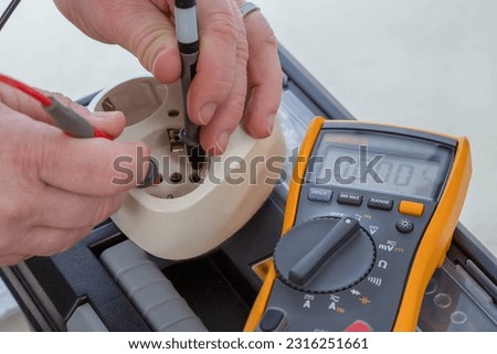 A closeup of a master's hands doing an electrical work with plug and fluke