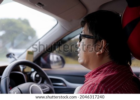 closeup mature Asian man with stress or fear or sad facial expression during sit and drive a car in traffic. GPS navigator on mobile phone. get loss. eyeglasses man on bad journey  