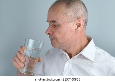 close-up of mature charismatic man, senior 60 years drinks clean water from glass, takes pill, concept most important element for life, human health, quench thirst
