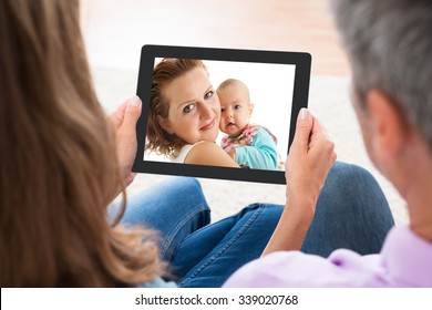 Close-up Of Mature Couple Looking At Photo On Digital Tablet