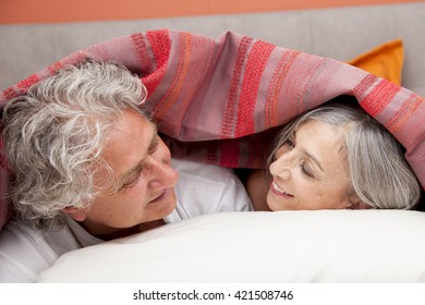 Close-up Of A Mature Couple Relaxing In Bed At Home